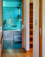 A bathroom features a striking metal tub against aqua tiles.
