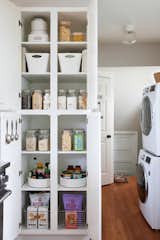 A dream of a pantry with Blisshaus pantry jars and labels and Hold Everything stackable glass canisters by Williams Sonoma. Alongside are LG efficiency stackable washer and dryer to maximize space.