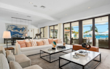 The airy living room features large glass doors  overlooking the pool and bay.