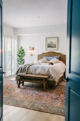Bedroom, Bench, Bed, Ceiling Lighting, Light Hardwood Floor, Wall Lighting, and Night Stands master bedroom through the blue doors  Photo 19 of 19 in A Mediterranean style urban oasis with warm industrial and bohemian eclectic twist by Saffron Bloom Antique Rugs