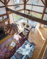 Living Room, Chair, Table, Wood Burning Fireplace, Medium Hardwood Floor, Standard Layout Fireplace, and Ceiling Lighting Interior - Existing timber frame, floor, fireplace and paneling  Photo 5 of 9 in Vermont Barn to High Performance Home by Robert D Swinburne