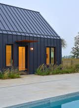 Detail of the black metal standing seam with the soft interior lighting surrounded by the prairie landscaping. 
