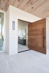 A solid-wood door welcomes guests from the covered front patio into the protected foyer.