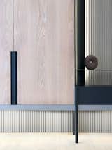 The custom-made cabinet wall with white washed oak panels and charcoal grey metal detail, resting in front of a striped backdrop. #studioadjective @studioadjective #apartment #home