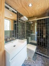 The bath w/ vertical running bond tile pattern and sliding glass shower door.