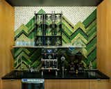 The backsplash in the coffee shop is made from variant hues of green glass tile, arranged in a herringbone pattern to resemble fir trees ascending the mountain peaks.