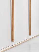 The millwork wall navigated the pinch point of the existing wall that stepped back and the white cabinet finish worked to further bounce any natural light deeper into the suite.
