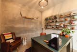 Two 10-foot concrete walls support the floating staircase and frame Luke's home office. A large military desk and reupholstered swivel chair, along with open shelving complete the room.