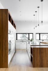 Kitchen, White Cabinet, Cooktops, Refrigerator, Wood Counter, Ceiling Lighting, Light Hardwood Floor, Wood Cabinet, Microwave, Pendant Lighting, Drop In Sink, and Wall Oven white/wood kitchen  Photo 16 of 25 in Résidence à Stoneham by Patriarche
