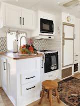 The compact kitchen features a ceramic tile backsplash. 