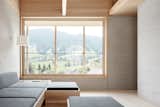Living Room, Light Hardwood Floor, Floor Lighting, Sofa, and Ottomans Large windows frame views of the rural Austrian valley.  Photo 6 of 14 in A Minimalist Home Is Built Into Steep Terrain in an Austrian Valley