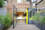 Outdoor, Back Yard, Grass, Small Patio, Porch, Deck, and Hardscapes The kitchen's structural pillar was painted a vibrant yellow, a shade that's echoed in the furnishings.  Photo 1 of 10 in A London Home With a 
Nightclub–Inspired Kitchen Is Listed For $2M