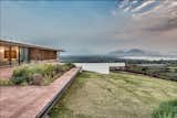 Outdoor, Slope, Large Patio, Porch, Deck, Grass, and Stone Patio, Porch, Deck The home is set on the top of a hill for prime views.  Photo 4 of 14 in A Modern Home in India Evokes Emotion With a Giant 4-Ton Rock