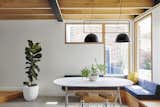 Dining Room, Concrete Floor, Pendant Lighting, Stools, Bench, and Table Filled with natural light and air-purifying plants, the two-bedroom abode boasts clean and contemporary character.

  Photo 4 of 13 in An Old Worker’s Cottage Is Reborn Into an Eco-Friendly Home and Learning Center