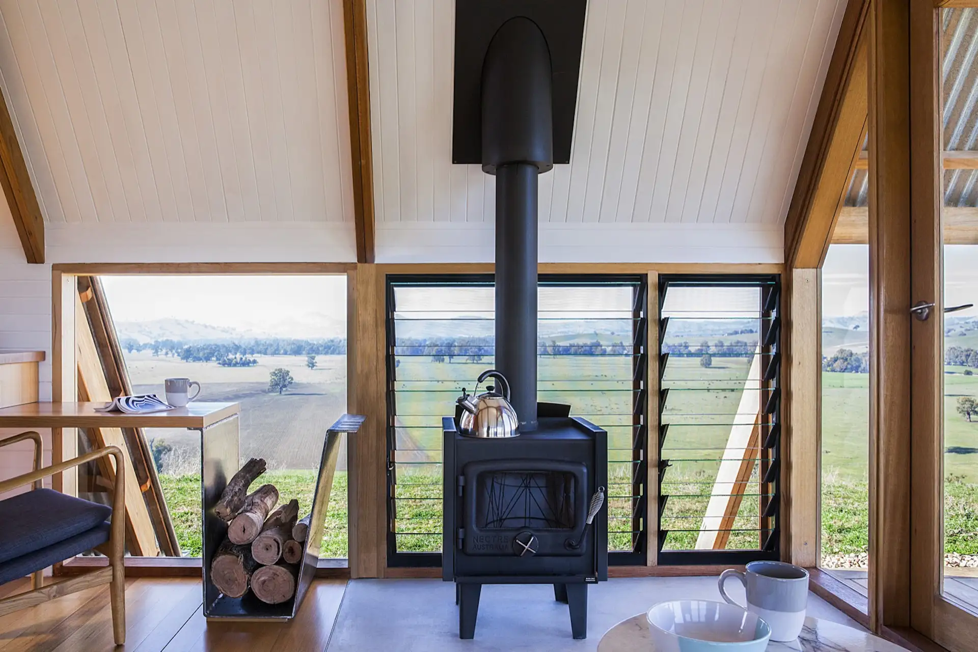 A freestanding Nectre wood-burning stove provides extra warmth in winter, while operable louvers let in cooling breezes in summer.