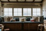 Living Room, Stools, Storage, Bench, Medium Hardwood Floor, and Wall Lighting A full-length window seat overlooks views of the beach and the bay.  Photo 8 of 11 in The Little Black Shack by Dwell from A 1920s Fisherman’s Shack in Australia Breathes New Life as a Cozy, Unique Rental