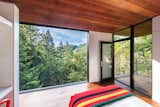 In the guest cabin, a sliding wall of glass opens the bedroom up to views of the forest. 