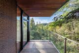 Outdoor, Woodland, Trees, Wood Patio, Porch, Deck, Wire Fences, Wall, and Small Patio, Porch, Deck The flat roof feature deep overhangs to shield the interior from solar heat gain.    Photo 12 of 14 in This Elegant Californian Prefab Minimizes Site Disturbance