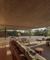 Living Room, Chair, Concrete Floor, Sofa, Table, Rug Floor, and End Tables The living room is furnished with low-lying timber furniture from studios like Ronan & Erwan Bourollec and Liceu de Artes e Ofícios.  Photo 6 of 16 in An Expansive Grass Roof Tops This Modern Brazilian Home