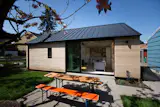 A dark gray standing seam metal roof tops the building with metal eaves that match the depth of the existing home. 