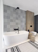 Black accents and patterns breath life into the bathroom with a freestanding tub. 