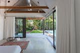 Bedroom, Recessed Lighting, Concrete Floor, Bed, Pendant Lighting, Rug Floor, and Night Stands Sliding glass doors dramatically open the master bedroom up to the outdoors.   Photos from A Minimalist Bungalow in Miami Welcomes a Sleek New Addition