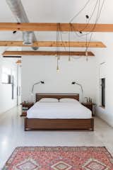 Looking for master bedroom lighting ideas for a vaulted ceiling? Try this one, where a gaggle of Edison bulbs are suspended from a vaulted ceiling and drape over an exposed beam in this otherwise sparse bedroom.&nbsp; &nbsp;