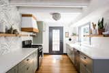 The white countertops are made from concrete and the wooden cabinets have been painted a subtle shade of sage. The floors are white oak hardwood.

