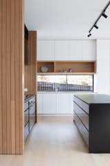 The white kitchen cabinetry is by Nikpol. The sink is integrated into a stainless steel benchtop.