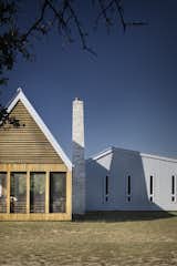 Exterior, Wood, House, Metal, Metal, Gable, and Saltbox The tapered limestone chimney draws inspiration from an existing shed built of dry-stacked local stone.

  Exterior Metal Wood House Metal Gable Saltbox Photos from A Stellar Sustainable Home Is Built on a Surprisingly Low Budget