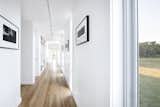 Hallway and Medium Hardwood Floor The main corridor, punctuated with full-height glazing, doubles as an art gallery.   Photo 9 of 17 in A Stellar Sustainable Home Is Built on a Surprisingly Low Budget