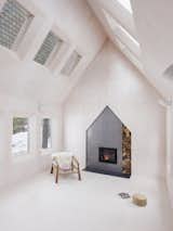 A wood-burning fireplace with a playful house-shaped surround anchors one end of the main living space.