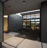 Outdoor, Garden, Shrubs, Concrete, Trees, and Boulders A look inside the entry courtyard flanked by the office to the west, the living area to the south, and the entrance to the east.

  Outdoor Boulders Trees Garden Concrete Photos from A High Desert Home Slides Open Like a Swiss Army Knife