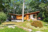 Built in 1956 by renowned local builder Vito Fosella, the two-story home embraces the wooded landscape with an exterior clad in teak, mahogany, and stone. The roof is tar and gravel. 