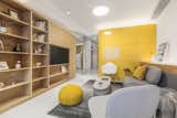 The living area has been carved out from the space between the yellow kitchen box and the wood-paneled entertainment box.