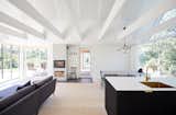 A white beamed ceiling adds structure to the open and airy living space bookended by immersive views of nature.