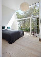 A 16-foot-tall wall of glass opens the master bedroom to views of the forest. 