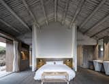 Bedroom, Concrete, Bed, Table, Night Stands, Storage, Rug, and Bench A timber beamed ceiling adds a rustic touch to the modern master suite.   Bedroom Bed Bench Storage Night Stands Concrete Photos from In Just 31 Days, These Historic Chinese Ruins Were Transformed Into a Chic B&B