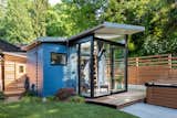 Blue-painted cedar siding wraps around the 169-square-foot Backyard Reading Retreat. The smaller wooden shed hidden in the rear houses a prefab dry sauna. 