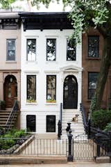 After: The original brownstone exterior was given a bright refresh with Farrow &amp; Ball’s Skimming Stone paint on the facade and Benjamin Moore’s Black for the trim, door, balusters, and handrails. The architectural designers also added new windows and doors.