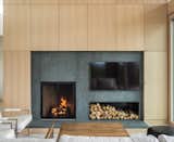 A custom wood-veneer paneled wall surrounds the wood-burning fireplace.

