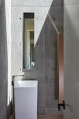 The powder room is framed with concrete walls and white oak floors, and is illuminated by a large skylight.