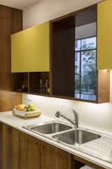 Kitchen, Laminate Cabinet, Recessed Lighting, Marble Counter, Wood Cabinet, and Drop In Sink An opening above the double sink frames views of the tree canopy.

  Photos from Greenery Breathes Fresh Life Into a Brazilian Midcentury