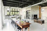 Dining, Shelves, Table, Chair, Painted Wood, Track, Storage, and Wood Burning Matte-black Tolix chairs surround a 14-foot harvest dining table that dates back to the 1800s.  Dining Wood Burning Table Painted Wood Photos from A 1920s Portland Warehouse Is Rehabbed Into an Industrial-Chic Home