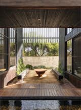 Outdoor, Shrubs, Small Patio, Porch, Deck, and Wood Patio, Porch, Deck An outdoor fire pit sits between the dining room and the study.  Photo 9 of 17 in Water Slices Through This Gorge-Inspired Australian House