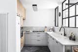 Kitchen, Porcelain Tile, Wall Oven, Ceiling, White, Cooktops, Refrigerator, Drop In, Engineered Quartz, Wood, and Accent Walls were torn down to create a bright, open kitchen.  Kitchen Cooktops Drop In Accent Refrigerator Wall Oven Photos from Budget Breakdown: A Stunning Apartment Revamp Mixes High and Low For Under $100K