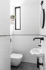 Lined with black porcelain tiles and complementary black fixtures, the half-bath was given a bright white refresh that instantly makes the tiny room feel more spacious.