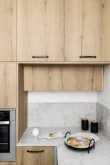 Kitchen, Wall Oven, Engineered Quartz Counter, Porcelain Tile Floor, and Wood Cabinet The kitchen countertops are quartz, and the cabinets are Formica.  Photos from Budget Breakdown: A Stunning Apartment Revamp Mixes High and Low For Under $100K