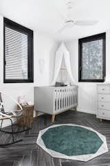 Bedroom, Ceiling, Rockers, Bed, Porcelain Tile, Rug, Storage, and Night Stands The second bedroom has been converted into a nursery.   Bedroom Bed Porcelain Tile Ceiling Photos from Budget Breakdown: A Stunning Apartment Revamp Mixes High and Low For Under $100K