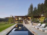 Outdoor, Trees, Stone Patio, Porch, Deck, Large Patio, Porch, Deck, Side Yard, Large Pools, Tubs, Shower, and Grass A large pool is located on the east side of the residence.   Photos from A Modern Montana House Mixes a Love of Art With the Outdoors